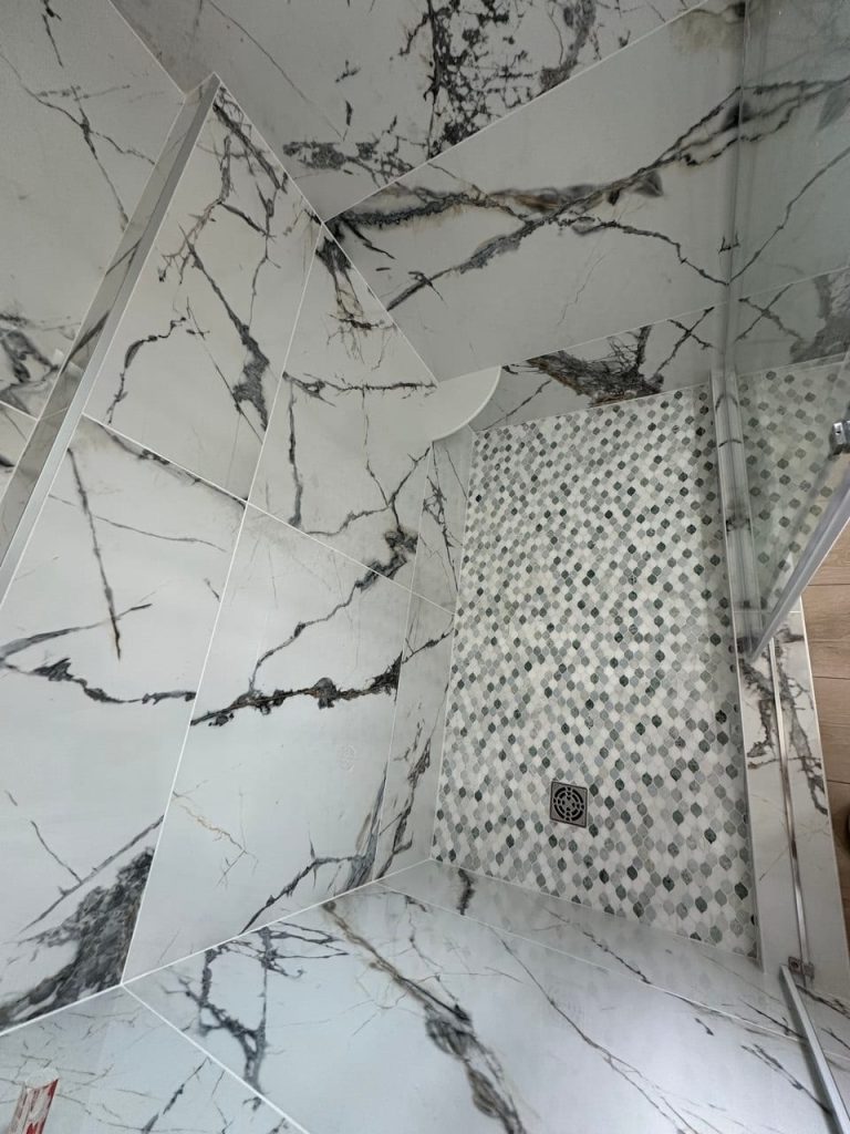 White Marble-Look Shower With an Arabesque Mosaic Floor