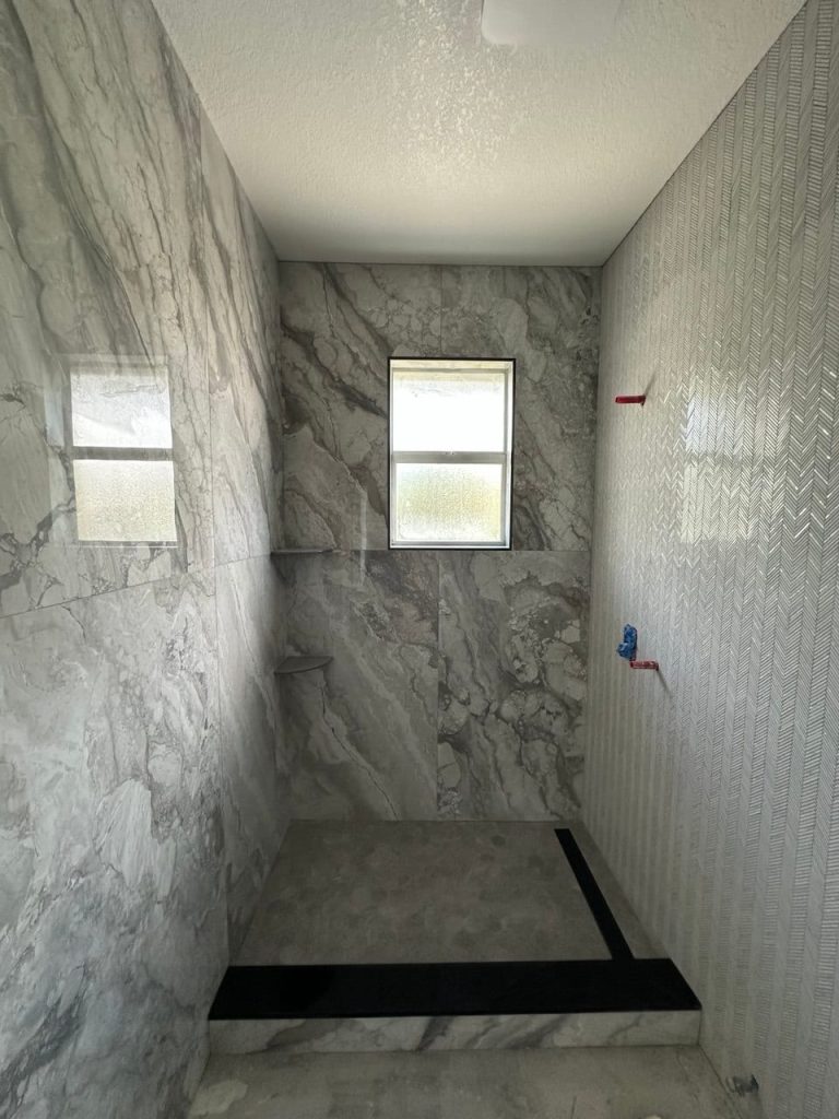 Gray Marble-Look Shower With a Chevron Mosaic Wall