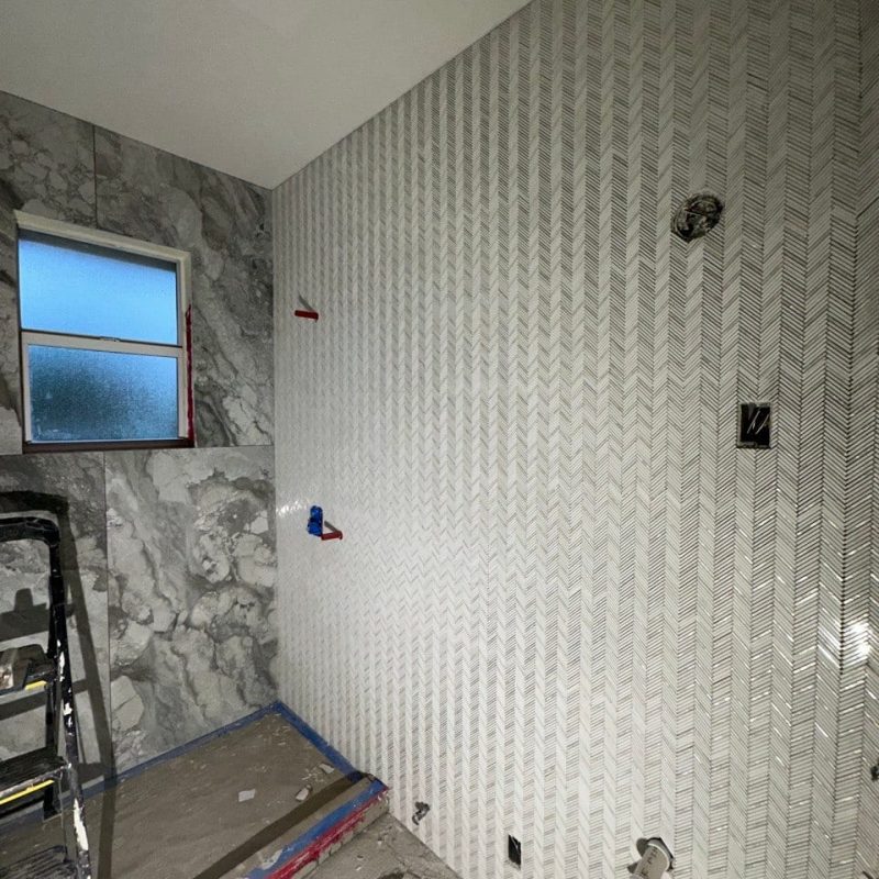 Gray Marble-Look Shower With a Chevron Mosaic Wall
